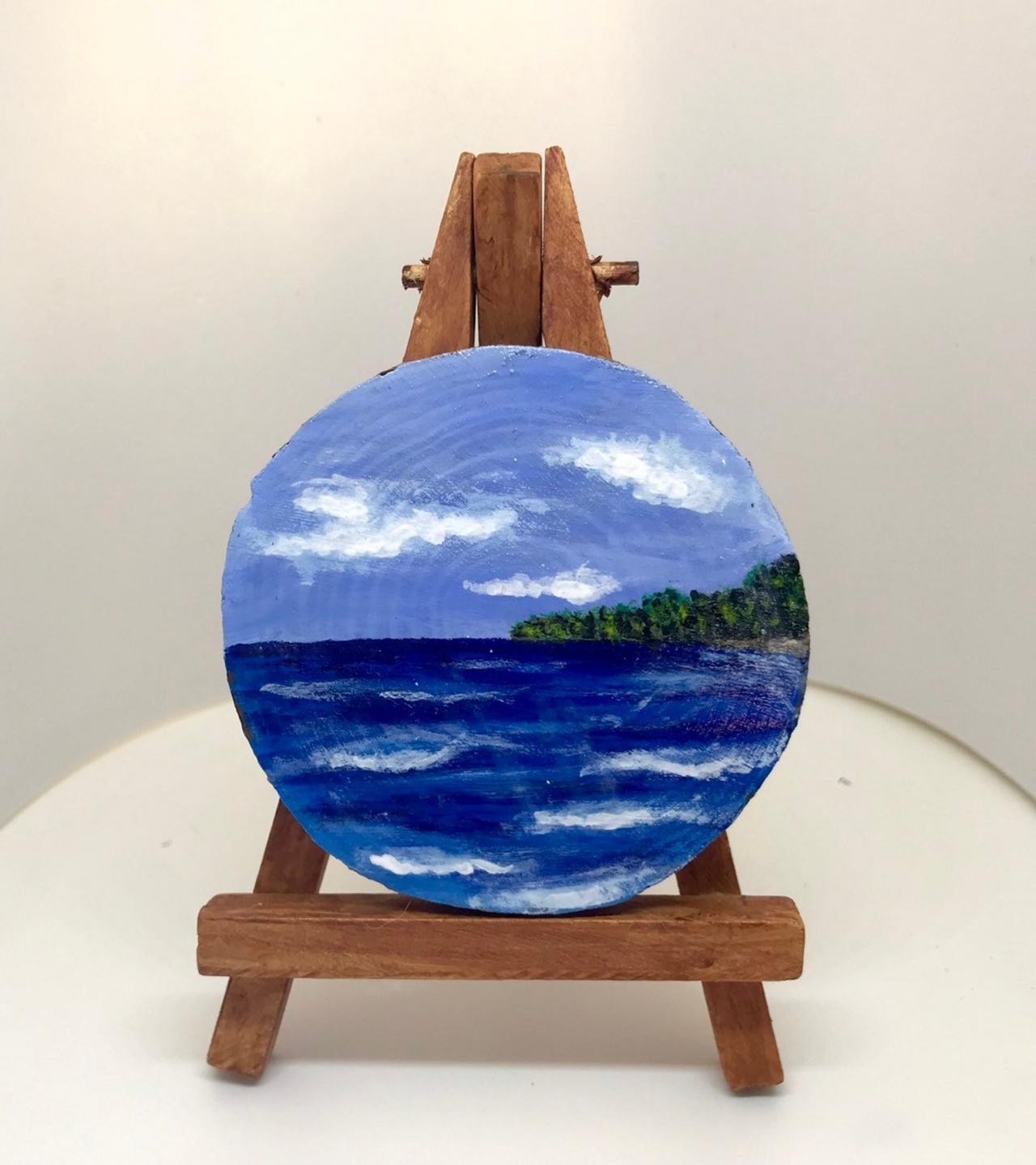 Mini painting of blue sky and sea on wood slice with easel